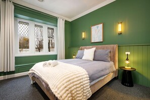 A bedroom with a bed, a window with curtains, a wall-mounted light, and a painting. - Stunning Renovated Red Brick Beauty on North - Gorgeous renovated three bedroom house in Albury (North Albury)