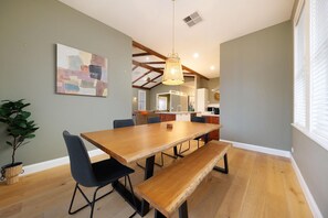 A dining area with a wooden table and chairs, a bench, a hanging light fixture, and a painting on the wall. - Stunning Renovated Red Brick Beauty on North - Gorgeous renovated three bedroom house in Albury (North Albury)