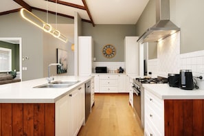 A modern kitchen with white cabinetry, a stainless steel sink, a gas stove, and a clock on the wall. - Stunning Renovated Red Brick Beauty on North - Gorgeous renovated three bedroom house in Albury (North Albury)
