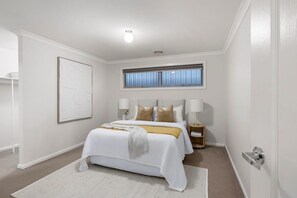 Ein Schlafzimmer mit einem Bett, Nachttischlampen, einem Fenster und einer Tür.