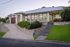 Ein modernes, zweistöckiges Haus mit einer Garage, einer überdachten Terrasse und einem gepflegten Rasen.
