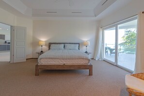 Ein Schlafzimmer mit einem großen Bett, zwei Nachttischen, einem Fenster mit Blick und einer Tür, die auf einen Balkon führt.