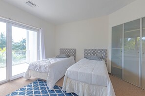 Un dormitorio con dos camas, un amplio ventanal corredero y un armario.