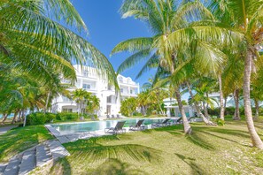 Un resort con piscina, palmeras y un edificio blanco.