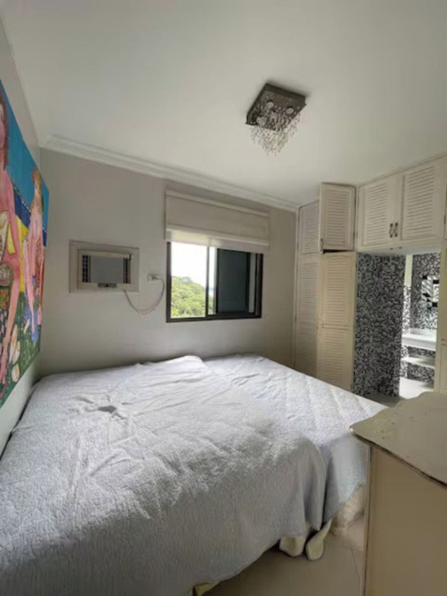 Un dormitorio con cama, ventana, lámpara de techo y vista parcial de un baño.