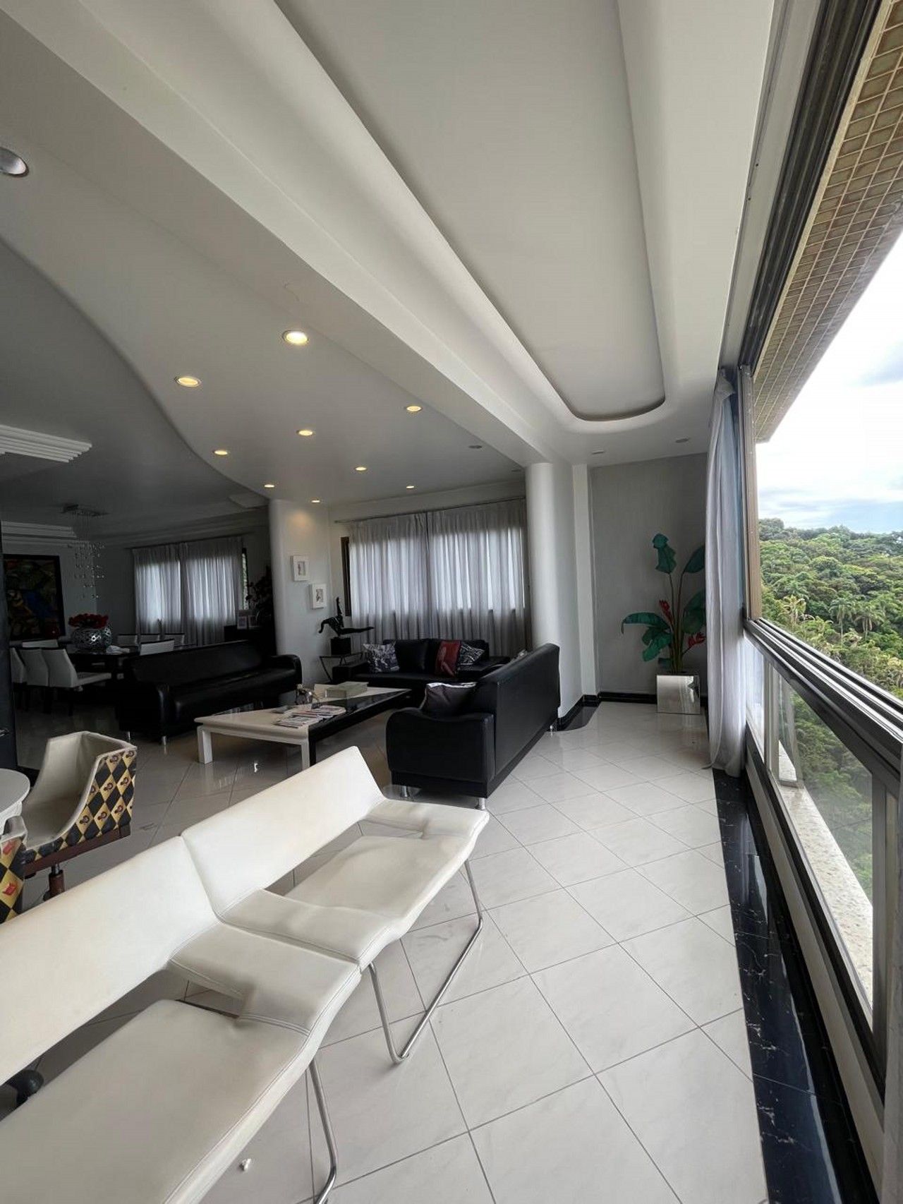 A spacious living area with a high ceiling, a dining area, and a view of the outdoors.