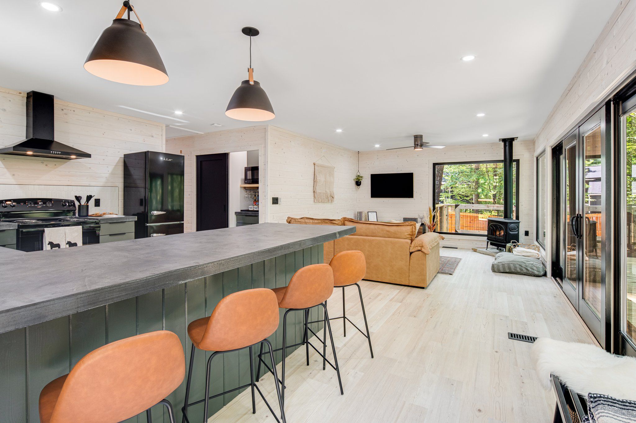 A modern kitchen with a central island, bar stools, a sofa, and a fireplace.