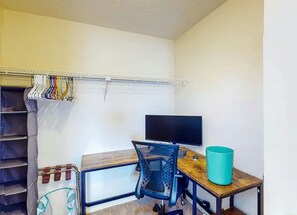 A room with a desk, chair, television, and a clothing rack. - Endless Summer - Gulf View - Sleeps 6! (Panama City Beach)