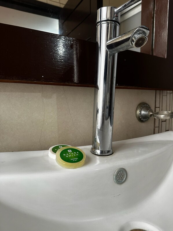 A bathroom sink with a chrome faucet and soap dispensers.
