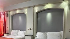 A hotel room with two beds, each with a headboard, a bedside table, and a red bedspread. - Hotel kristal (La Barca)