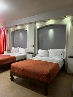 A hotel room with two beds, each with a headboard, a bedside table, and a red bedspread. - Hotel kristal  (La Barca)