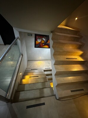 Una escalera con barandilla, un letrero en la pared y una obra de arte enmarcada.
