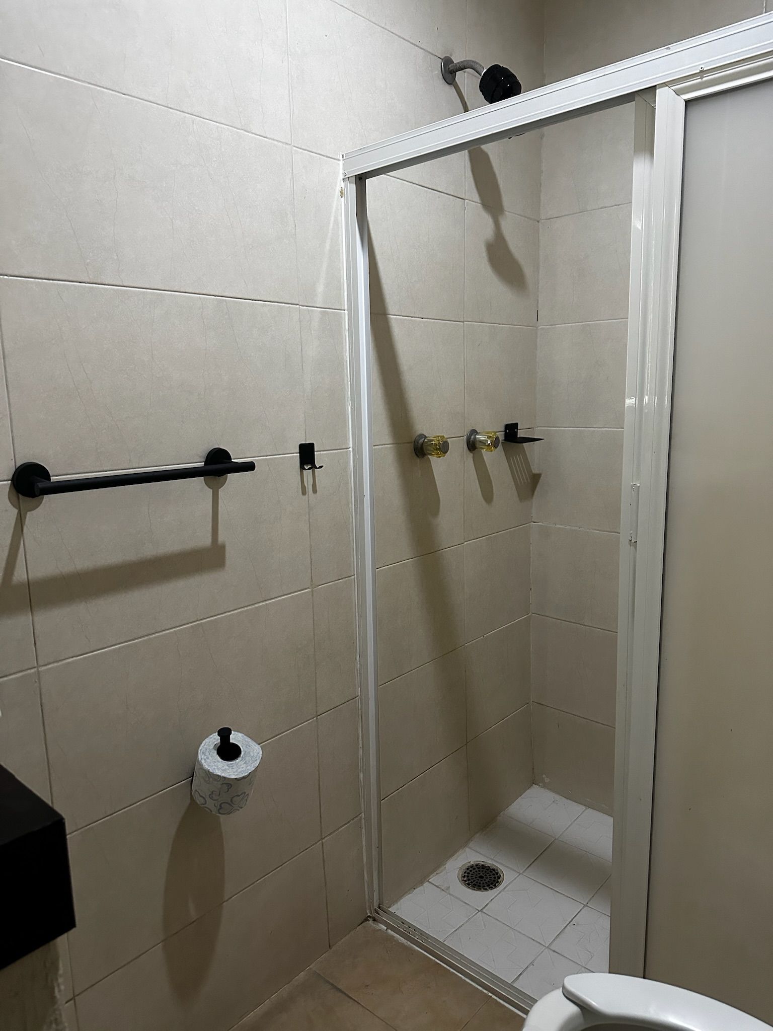 Un baño con cabina de ducha, inodoro y toallero.