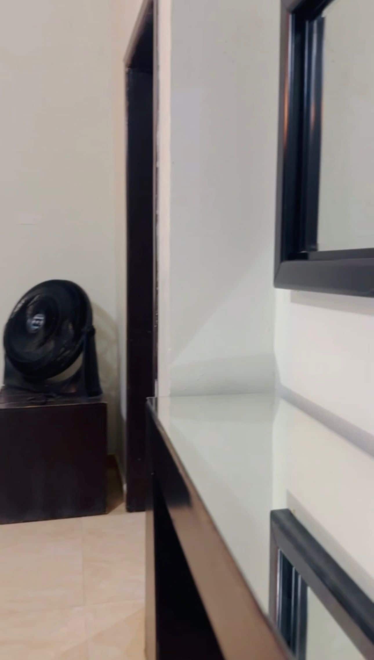 A room with a bed, a small table, and a black object on the table.