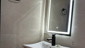 A bathroom with a white sink, black countertop, and a mirror with a light. - Hotel kristal (La Barca)