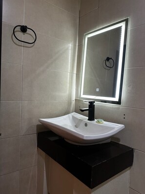 A bathroom with a white sink, black countertop, and a mirror with a light. - Hotel kristal  (La Barca)