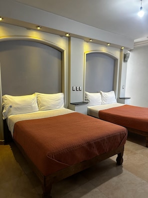 A hotel room with two beds, each with a headboard, a bedside table, and a wall-mounted light. - Hotel kristal  (La Barca)