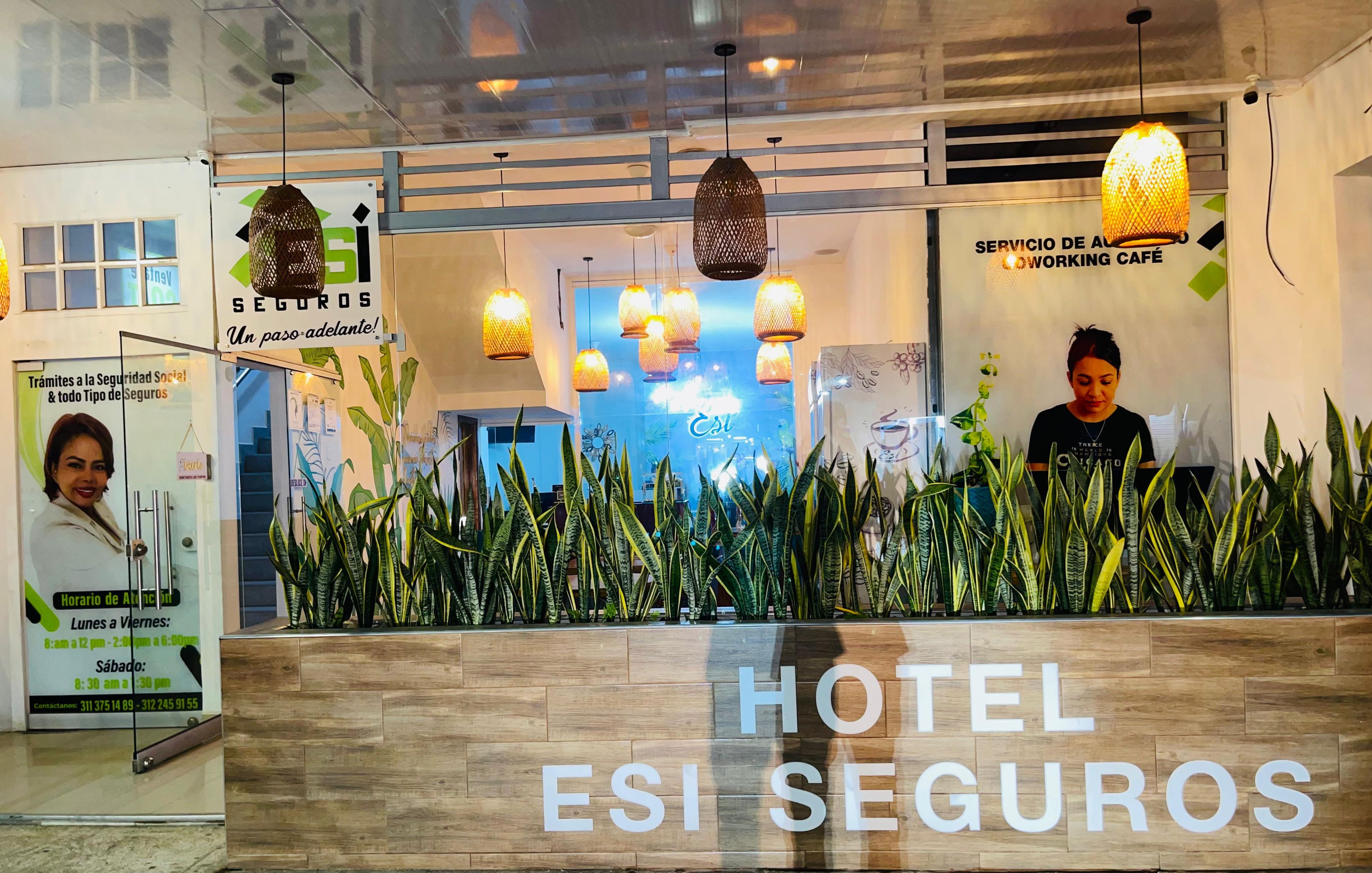 En reception med en bardisk i trä, hängande taklampor och en stor skylt med texten ”HOTEL ESI SEGUROS”.