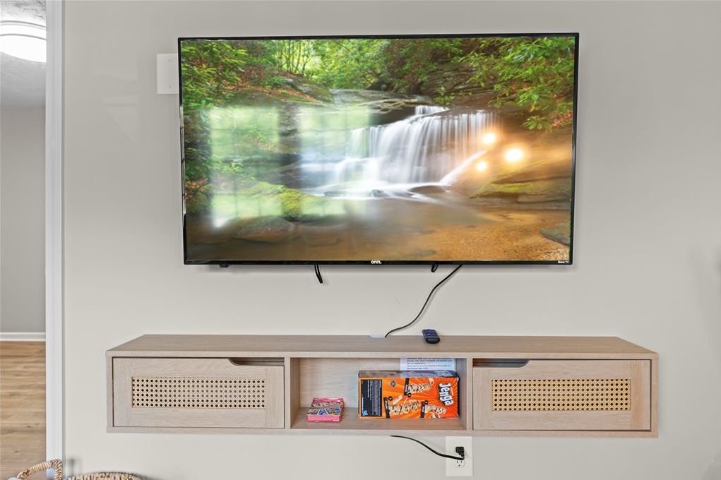 A television mounted on a wall with a wooden shelf below it.