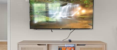 A television mounted on a wall with a wooden shelf below it.