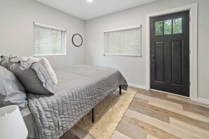 A bedroom with a bed, two windows, a door, and a rug. - Saratoga Unit 10 minutes to everything! (Ballston Spa)