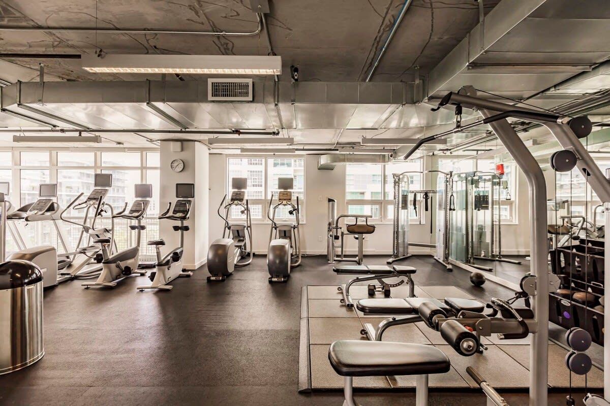 A gym with various exercise equipment, large windows, and a clean, modern design.
