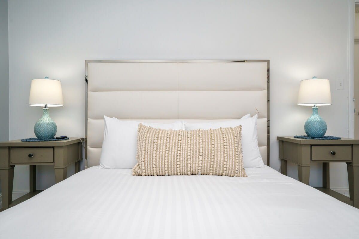 Quarto de hotel com uma cama grande, duas mesas de cabeceira e luminárias.