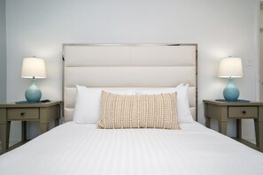 Quarto de hotel com uma cama grande, duas mesas de cabeceira e luminárias.
