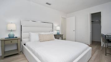 A bedroom with a bed, bedside tables, a desk, and a chair.