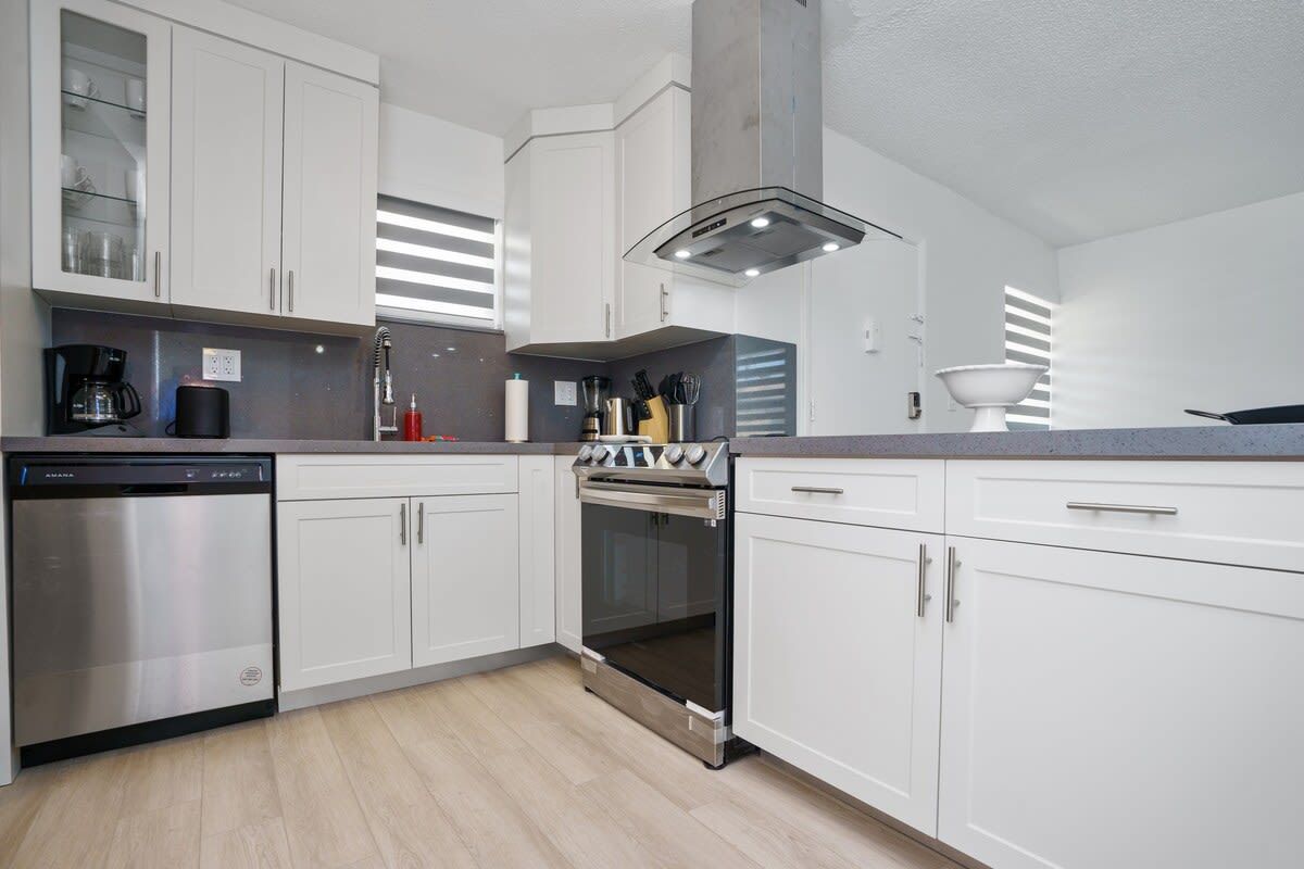 Una cocina moderna con armarios blancos, electrodomésticos de acero inoxidable y una encimera gris.