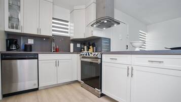 Una cocina moderna con armarios blancos, electrodomésticos de acero inoxidable y una encimera gris.