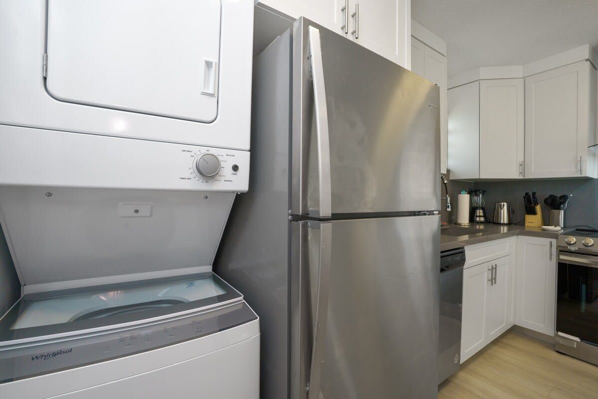 Una cocina con refrigerador de acero inoxidable, lavavajillas y horno empotrado.