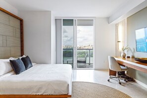 A modern hotel room with a bed, a desk, a chair, and a large window offering a city view. - Biscayne Bay Views Studio Central in Miami (Miami)