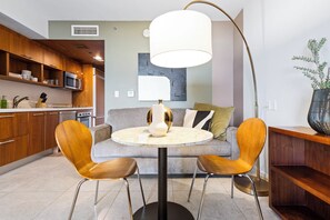 A modern living space with a round table, two chairs, a sofa, a large floor lamp, and a kitchen area. - Biscayne Bay Views Studio Central in Miami (Miami)