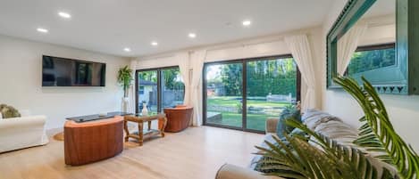 A spacious living room with a sofa, a coffee table, and a TV mounted on the wall.