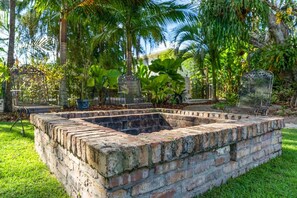 A brick structure with metal chairs, surrounded by lush greenery. - Garden House, Pool in Lush Peaceful Homestead (Homestead)