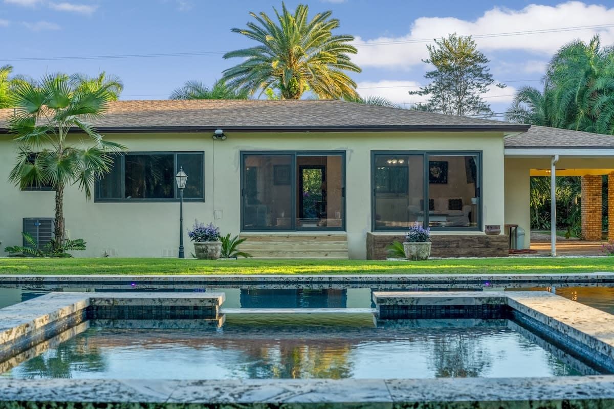 Une maison moderne à deux étages, dotée d’une piscine, de grandes fenêtres et d’une pelouse bien entretenue.