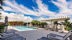 Un espace piscine doté de chaises longues, d’une pergola et d’une clôture blanche.