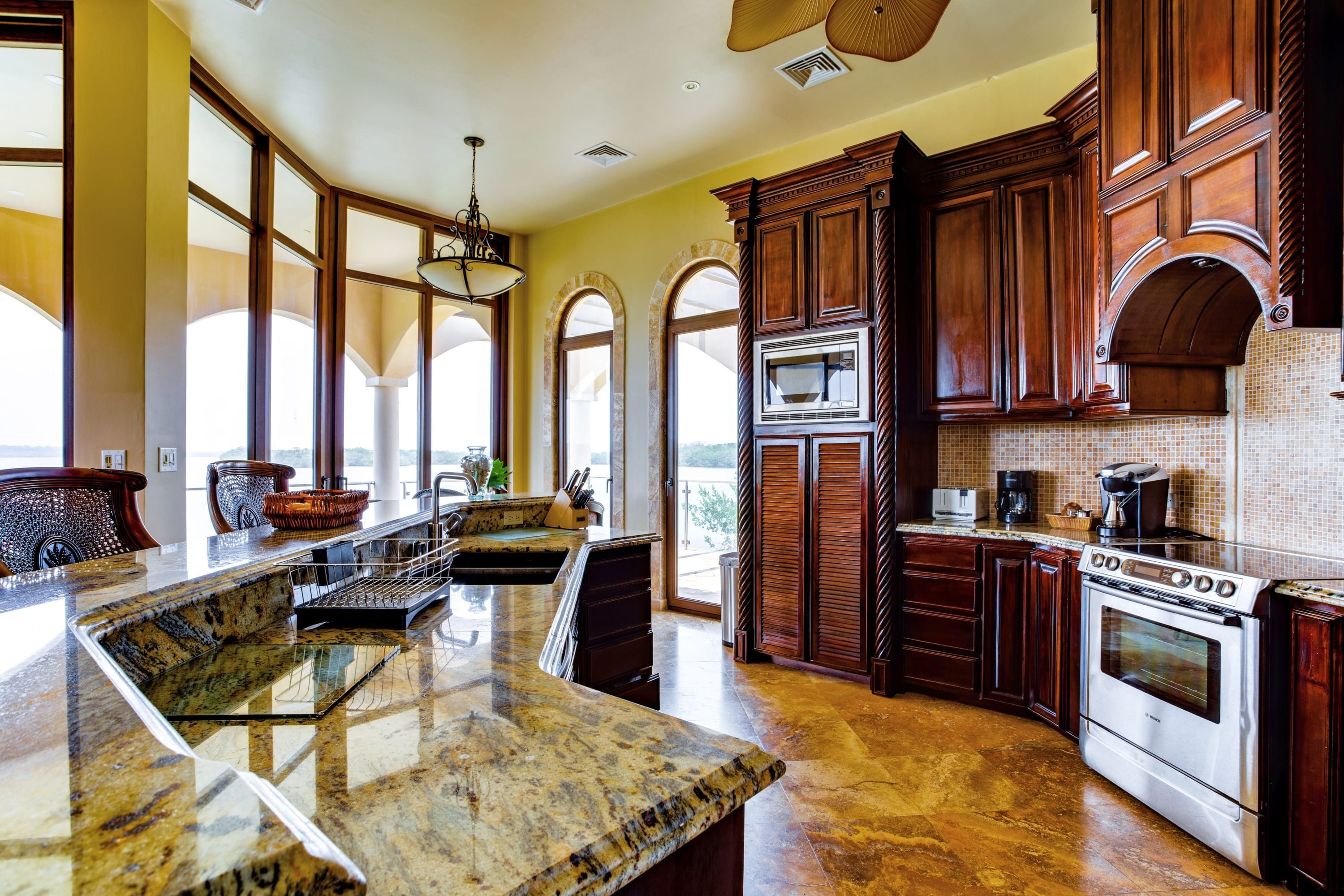 A spacious kitchen with granite countertops, a Bosch oven, and wooden cabinetry.