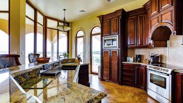 A spacious kitchen with granite countertops, a Bosch oven, and wooden cabinetry.
