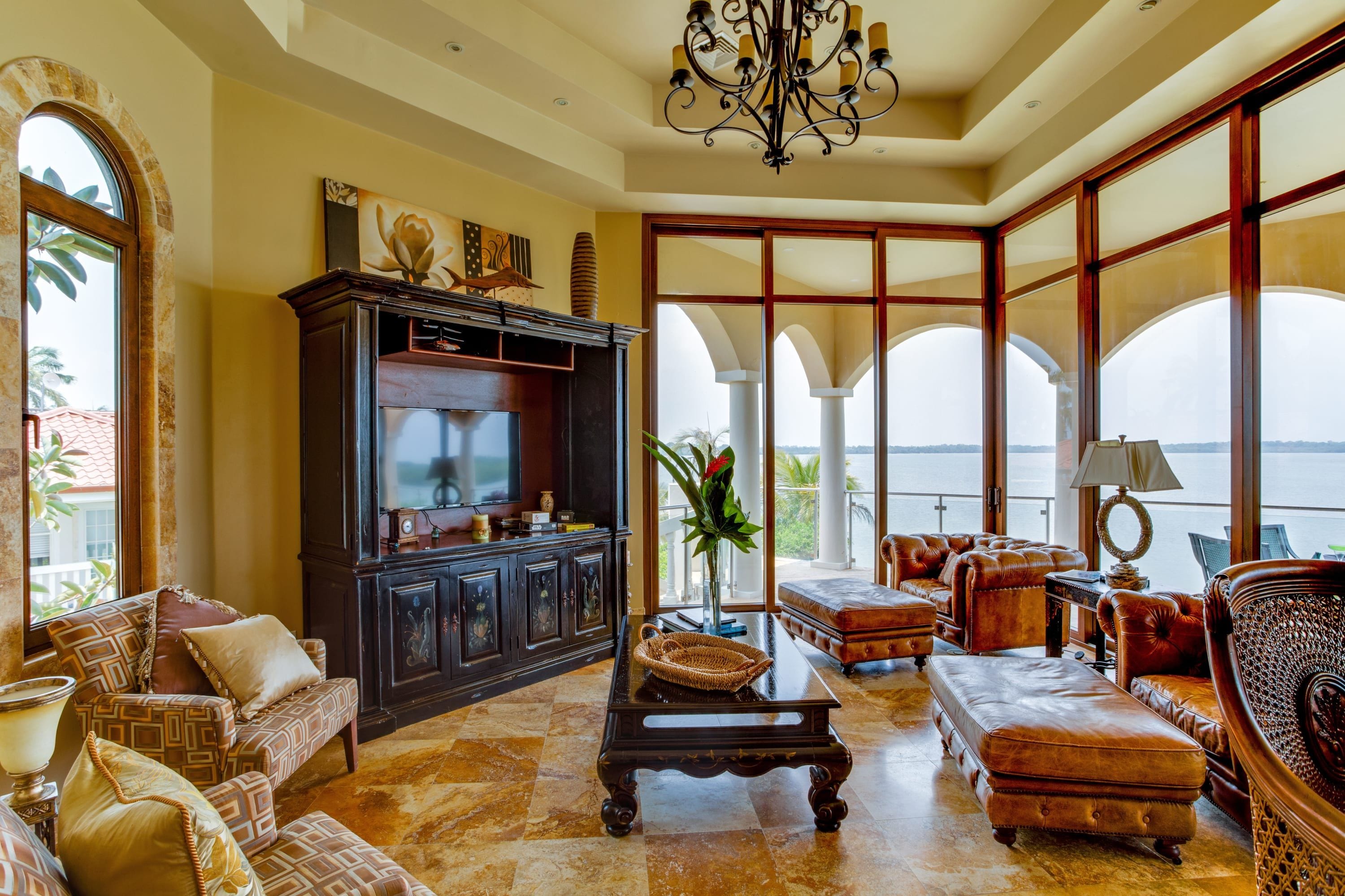 A spacious living room with a fireplace, comfortable seating, and large windows offering a view of the sea.
