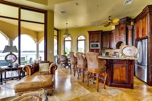 A spacious kitchen with a bar area, large windows, and a view of the outdoors.
