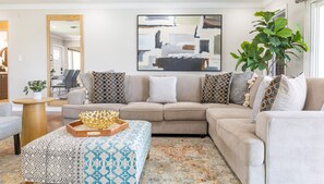 Una sala de estar con un sofá, un reposapiés y un cuenco decorativo.