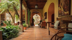 A covered outdoor area with a stone archway, wooden benches, and potted plants. - Boutique Magia Stay, Pool in Antigua (Antigua Guatemala)