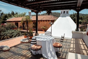 A terrace with a round table and chairs, a white structure, and a building with a red-tiled roof in the background. - Boutique Magia Stay, Pool in Antigua (Antigua Guatemala)