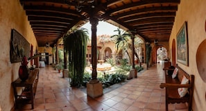 A covered outdoor area with tiled flooring, wooden benches, and potted plants. - Boutique Magia Stay, Pool in Antigua (Antigua Guatemala)