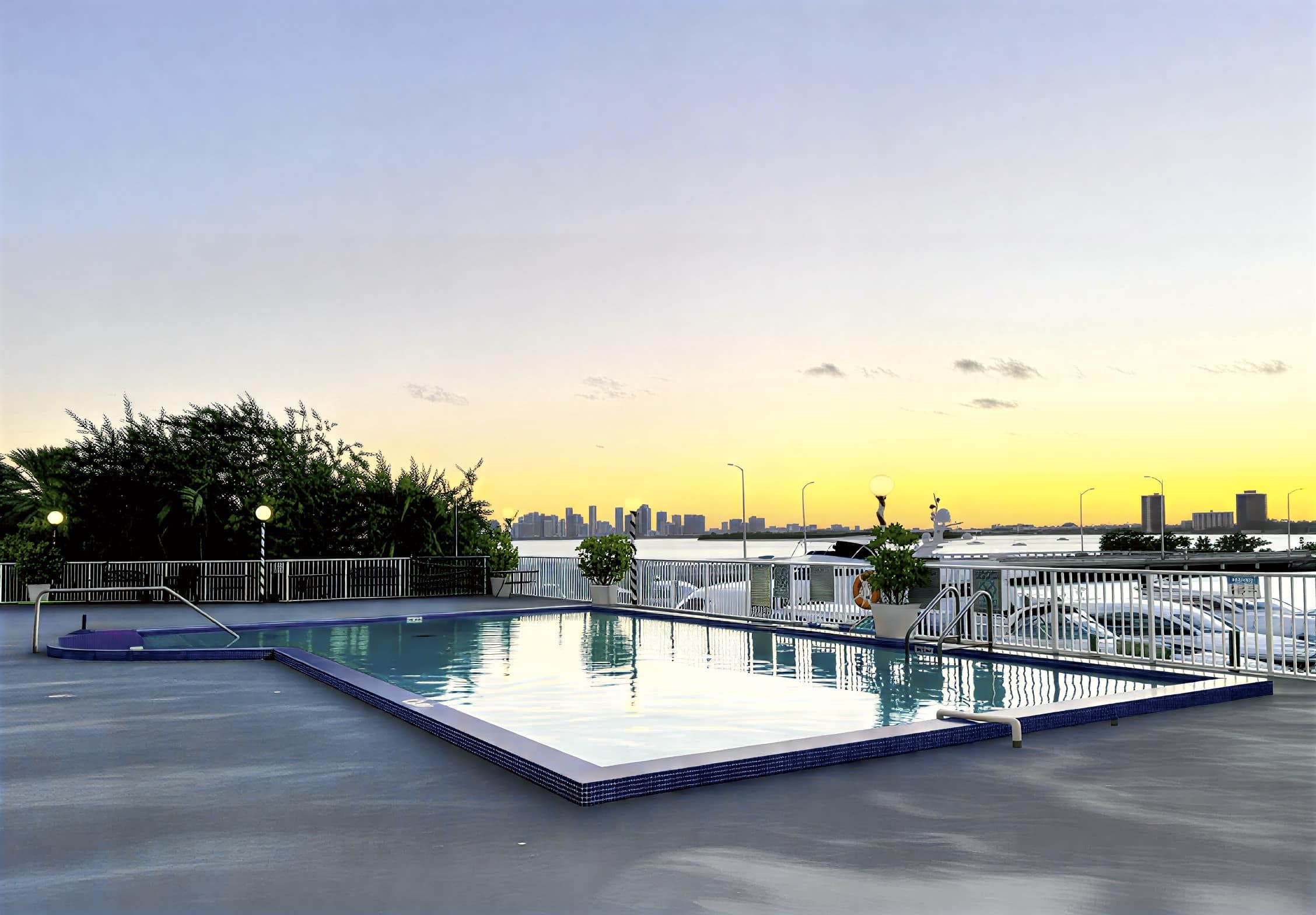 Piscina no terraço com vista para o horizonte urbano ao pôr do sol.