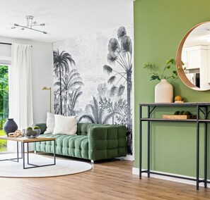 Una sala moderna con un sofá verde, una mesa de centro redonda y un mural en la pared.