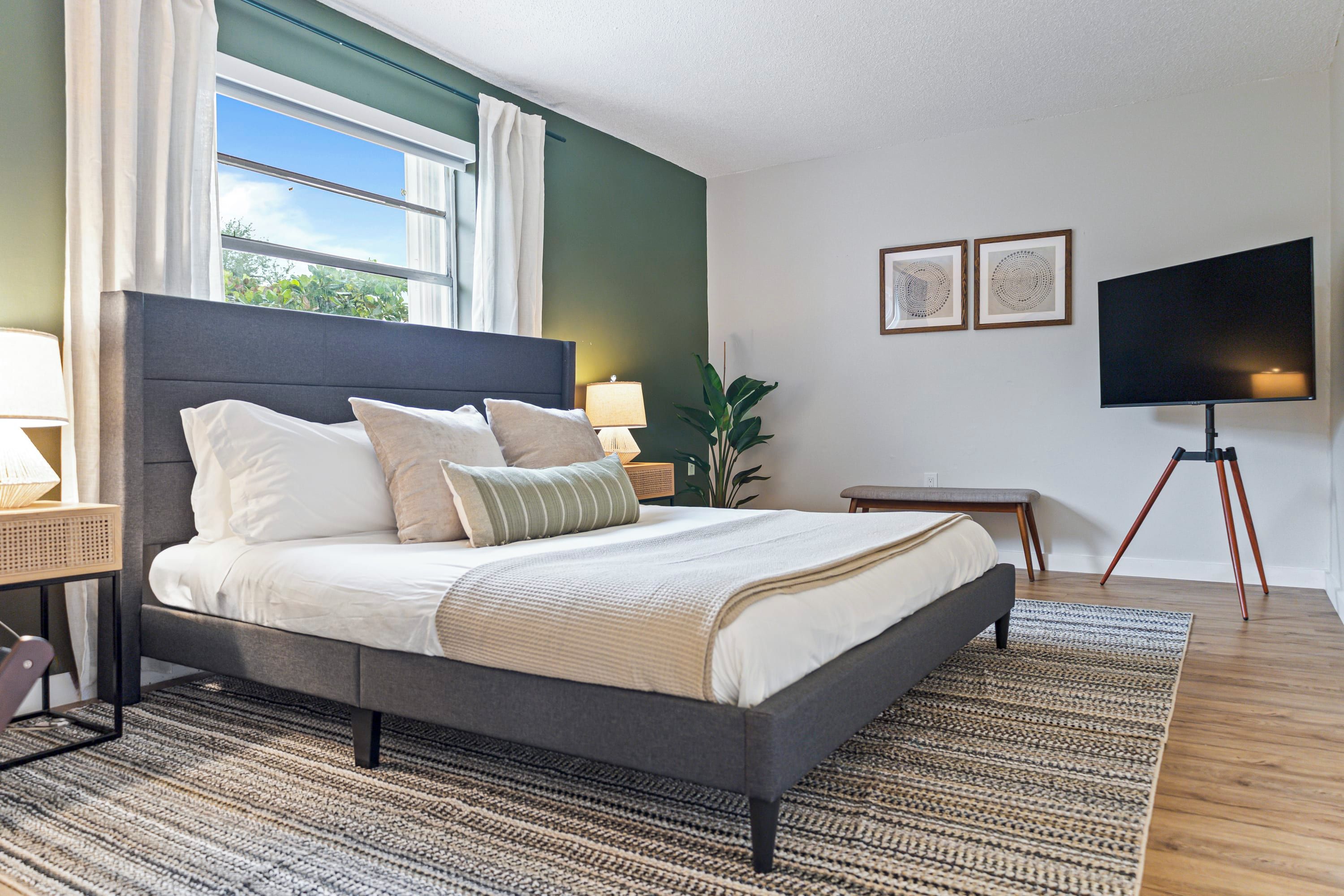 Una camera da letto moderna con un letto grande, una TV e una finestra con tende.