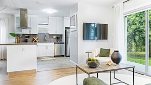 Una cocina moderna con gabinetes blancos, electrodomésticos de acero inoxidable y un comedor con mesa y sillas verdes.